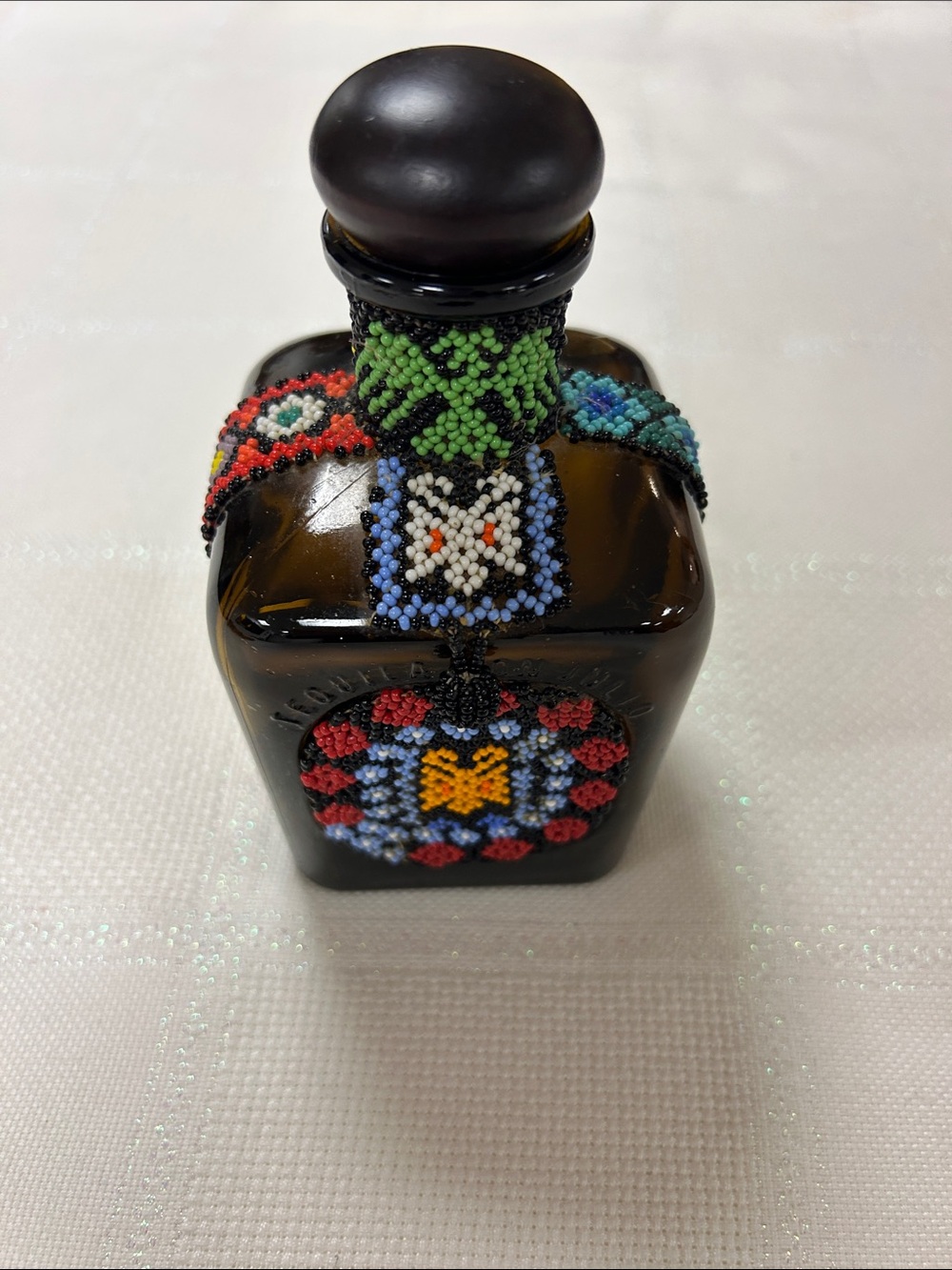 artisanal amber tequila bottle covered in traditional Wixárika (Huichol) beads